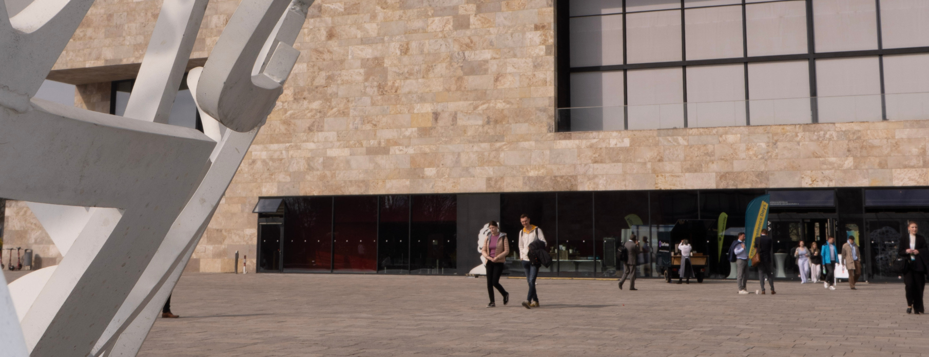 Logo der M&A Days Campus Westend mit FLOW THE KITCHEN Schriftzug vor einer Steinwand